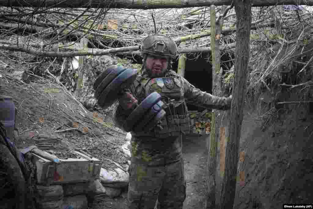 Український військовий, стоячи в окопі, піднімає важку гантель. Каже, що бійці стільки часу тримають цю позицію під Бахмутом, що почали вже називавати це місце &laquo;домом&raquo;. Донеччина, Україна. 3 березня 2024 року &nbsp;