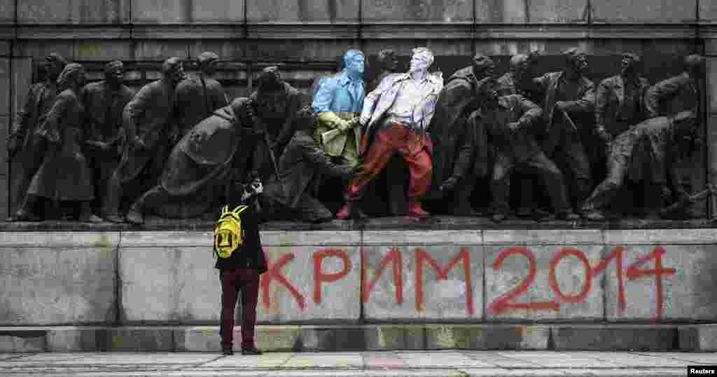 Martie 2014: Doi soldați de pe monument sunt pictați în culorile Ucrainei și Poloniei. Mesajul de dedesubt face referire la invazia Crimeei și la masacrul din pădurea Katyn din 1940, când armata sovietică a ucis 22.000 de prizonieri polonezi.