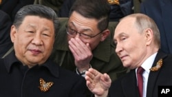 Президент Росії Володимир Путін (праворуч) та президент Китаю Сі Цзіньпін (ліворуч) розмовляють під час військового параду до Дня Перемоги в Москві, Росія, 9 травня 2025 року