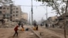 Copiii umplu recipiente cu apă printre clădirile nivelate de bombardamentele israeliene în Rafah, în sudul Fâșiei Gaza, pe 25 februarie 2024.