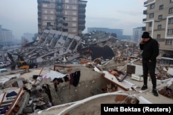 Zelzeleden soñ yıqılğan bina üstünde turğan er adamı. Hatay, Türkiye, 2023 senesi fevralniñ 7-si