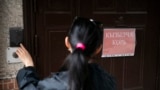 Woman rings the doorbell with the inscription measles at Republican Infectious Diseases Clinical Hospital, Bishkek city, Kyrgyzstan.
