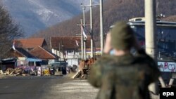 Pripadnik KFOR-a posmatra barikade u selu Zupče - ilustracija