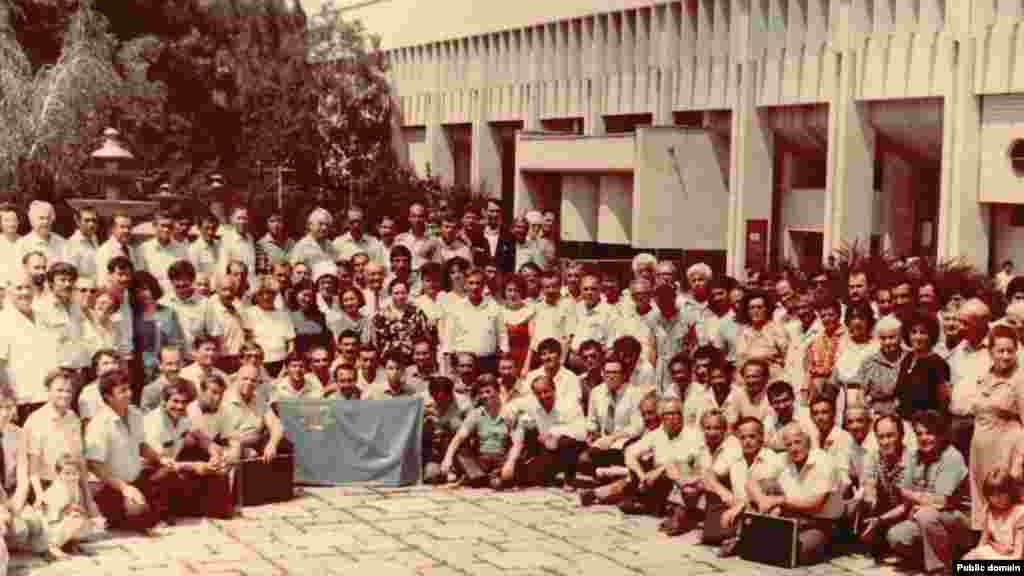 1991 senesi iyün ayı. Bular Aqmescitteki ekinci Qurultaynıñ iştirakçileri ve musafirleri. Eki Qurultay arasında 70 yıldan çoq vaqıt keçti. Sürgünlikten Vatanına qaytıp kelgen qırımtatarlarnıñ qollarında 20-nci asırnıñ başında tasdıqlanğa Milliy bayraq&nbsp; 