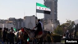 Syria - A man holding a flag adopted by Syria's new rulers rides a horse, after Syria's Bashar al-Assad was ousted, in central Damascus, December 15, 2024. 