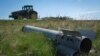 Un fragment dintr-o rachetă rusească zace pe un câmp în timp ce un fermier își lucrează pământul în regiunea Harkov din Ucraina, devastată de război.
