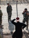 Сирийский друз разговаривает с израильскими солдатами через решетку и колючую проволоку на линии размежевания на Голанских высотах. Мадждаль-Шамс, 17 июля 2025 года