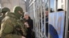 Ukraine -- A Ukrainian woman speaks with armed men in military uniform, believed to be Russian Soldiers, who block Ukrainian navy base in Novoozerniy village near of Yevpatoriya, Crimea, March 3, 2014