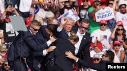 ABŞ-nyň ozalky prezidenti Donald Tramp mitingiň bolan ýerinden äkidilýär. 13-nji iýul
