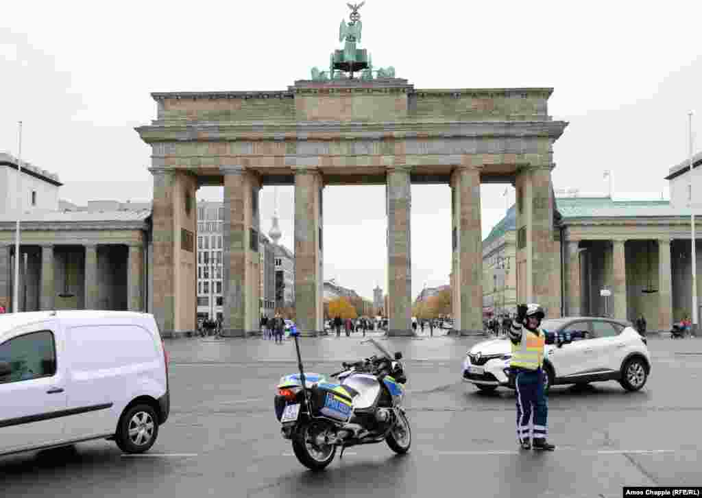 Soldați de gardă din estul Berlinului stând pe bordura de deasupra Zidului Berlinului, în fața Porții Brandenburg, pe 11 noiembrie 1989, la două zile de la &bdquo;prăbușirea&rdquo; Zidului. Cu alte cuvinte, pe 9 Noiembrie 1989, după ce un oficial est-german a anunțat că punctele de trecere ale Zidului vor putea fi traversate de civili fără probleme și &bdquo;fără întârziere&rdquo;, zeci de mii de oameni au trecut în cursul nopții în Berlinul de Vest. Pentru prima dată de când fusese ridicat, Zidul nu a mai fost impenetrabil și a început să fie demolat.&nbsp;