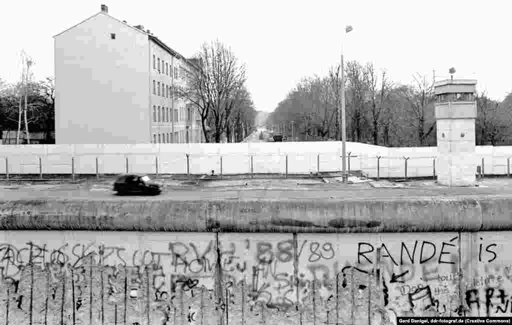 O mașină militară, patrulând de-a lungul Fâșiei Morții, pe mijlocul străzii Bernnauer, în 1989. Pentru construcția Zidului în acest loc a fost distrus inclusiv un cimitir.&nbsp;