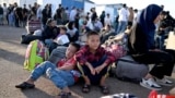 Afghan refugees rest with their belongings after arriving at the zero point of the Islam Qala border crossing between Afghanistan and Iran on June 28, 2025, following their deportation from Iran.
