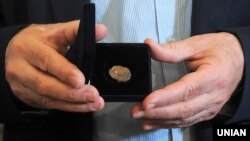 Директор Центру археології Києва Інституту археології України Михайло Сагайдак демонструє реліквію періоду України-Русі – печатку князя Святослава Хороброго (правління: 964–972) із зображення двозуба (праобразу державного герба України – тризуба). Київ, 11 травня 2016 року 