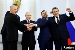 Rusiye prezidenti Vladimir Putin (ortada) Rusiyeniñ işğal etilgen dört Ukrayına toprağınıñ ilhaqını ilân etüv mukâfatında. Moskva, 2022 senesi sentâbrniñ 30-ı