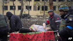 Lucrătorii de urgență și voluntari ucraineni transportă o gravidă rănită dintr-o maternitate avariată în urma unui atac aerian la Mariupol, Ucraina, pe 9 martie 2022. Imaginea apare într-o scenă din documentarul „20 de zile la Mariupol”. 